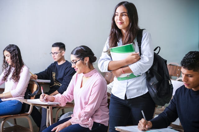Person holding textbooks, gesturing cost of higher education for family